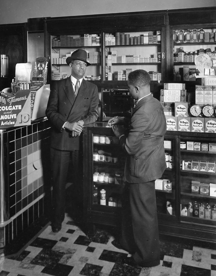 Two men talk at the counter of a general store